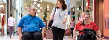 male and female wheelchair users out shopping in Milton Keynes with friend, chatting and smiling