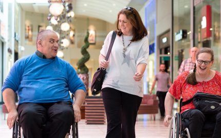 male and female wheelchair users out shopping in Milton Keynes with friend, chatting and smiling