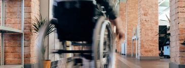 blurred wheelchair moves through office environment