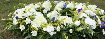 white and purple coloured funeral flowers on ground