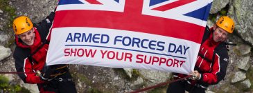 Two climbers holding large armed forces day flag ©UK MOD Crown Copyright 2022
