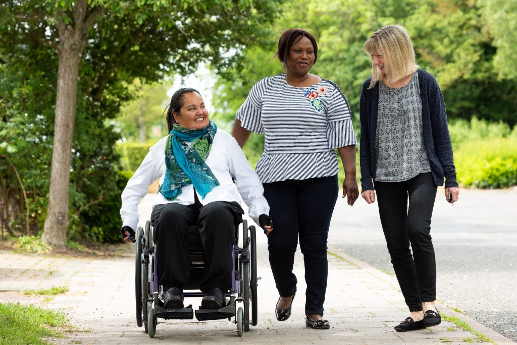 wheelchair user spinal injured person outside with two fellow walkers
