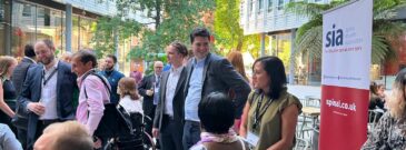 Group of people at corporate Fundraising event in city environment with SIA banner