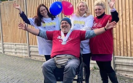 man in wheelchair and team of fundraisers with hands up wearing SIA t-shirts