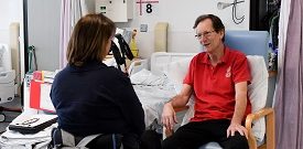 SIA Advisor Peta in wheelchair sat opposite and talking to hospital patient