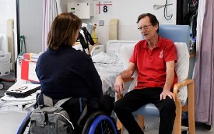SIA Advisor Peta in wheelchair sat opposite and talking to hospital patient