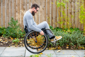 back-up-wheelchair-skills. Man wheelies down small step on path