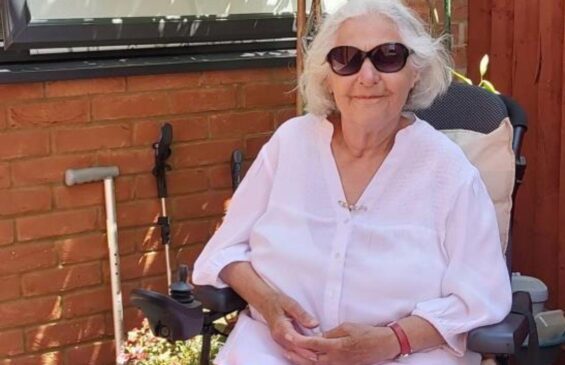 SIA member Maria Clark sat in wheelchair wearing sunglasses